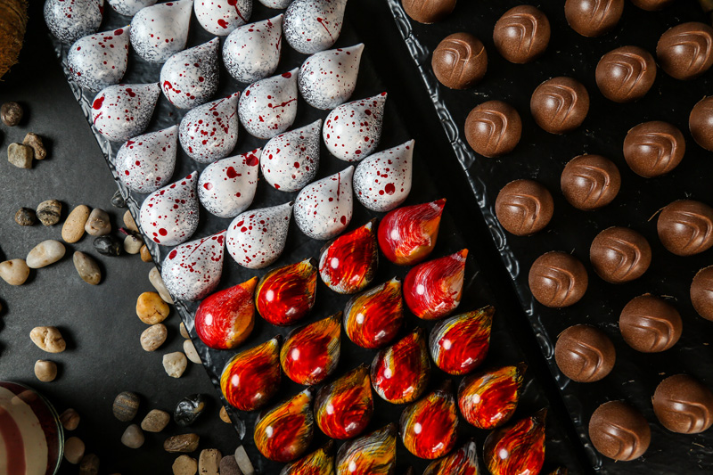 top view colored decorative chocolates on a stand with stones on a black background